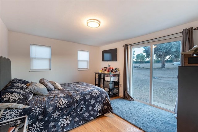 bedroom with access to exterior and hardwood / wood-style floors