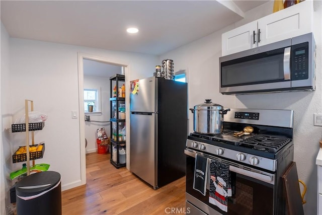 kitchen featuring appliances with stainless steel finishes, light hardwood / wood-style flooring, and white cabinets