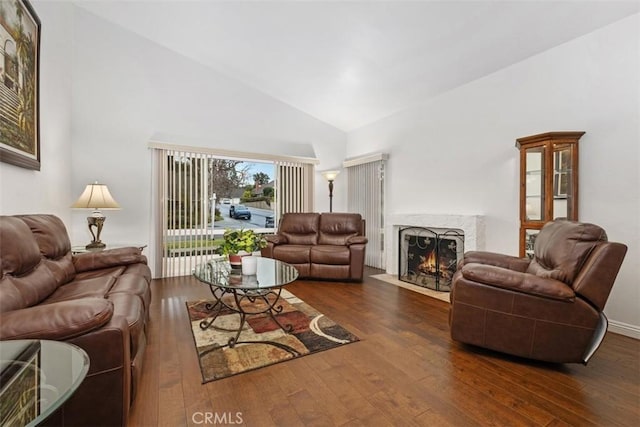 living room featuring dark wood-type flooring, a premium fireplace, and high vaulted ceiling