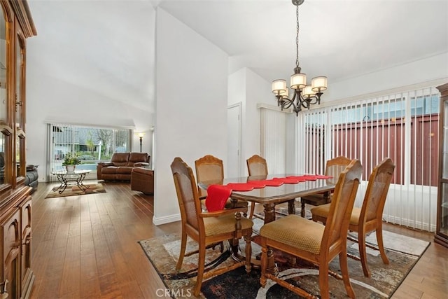 dining space with an inviting chandelier, wood-type flooring, and a high ceiling