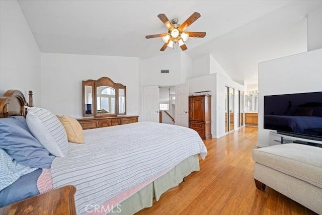 bedroom with connected bathroom, high vaulted ceiling, ceiling fan, and light wood-type flooring