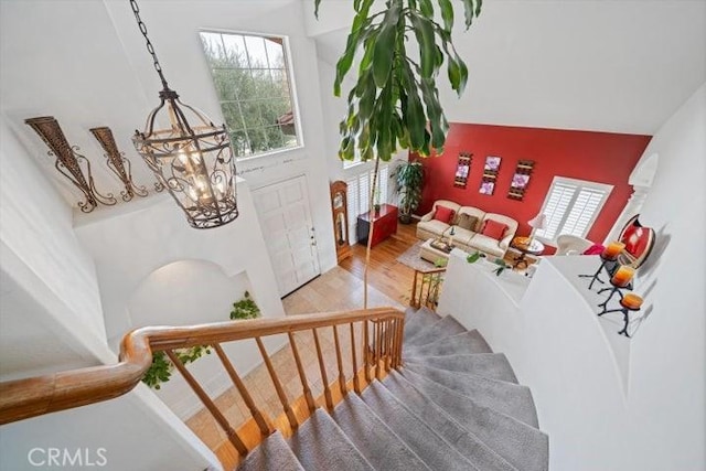 staircase with hardwood / wood-style flooring, a high ceiling, and a notable chandelier