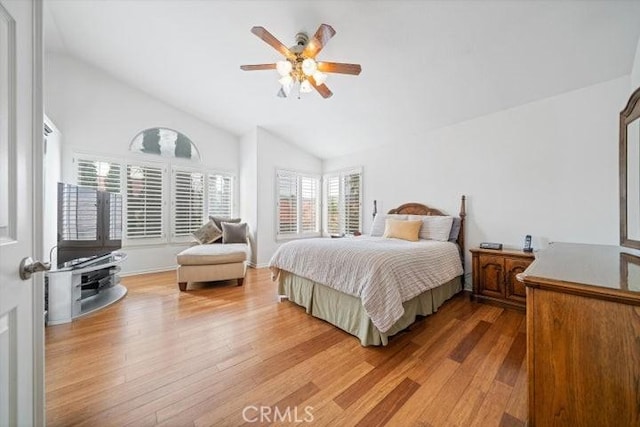 bedroom with ceiling fan, vaulted ceiling, and light wood-type flooring