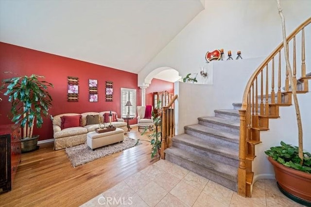 living room featuring wood-type flooring, high vaulted ceiling, and decorative columns