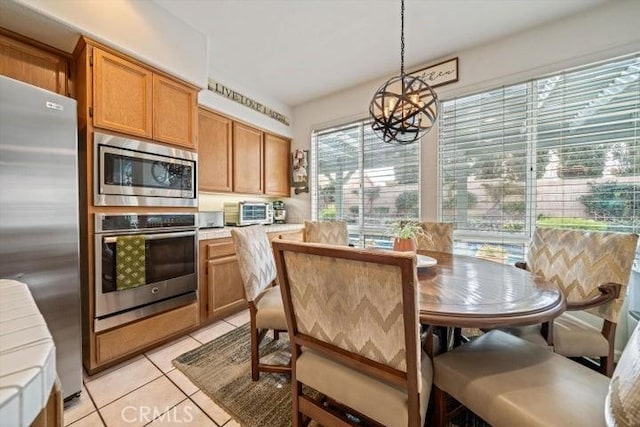 kitchen featuring tile countertops, light tile patterned floors, a notable chandelier, pendant lighting, and stainless steel appliances