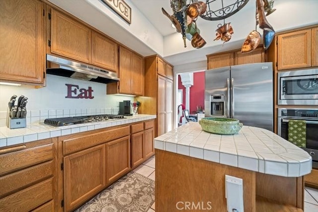 kitchen featuring appliances with stainless steel finishes, a center island, tile countertops, and light tile patterned floors