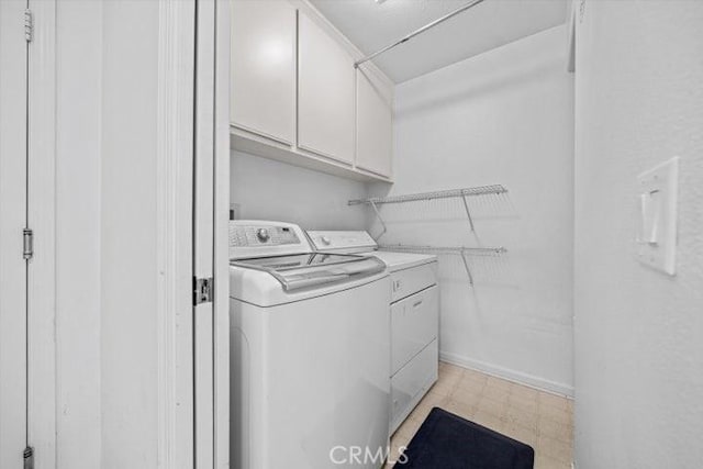 clothes washing area with washer and clothes dryer and cabinets