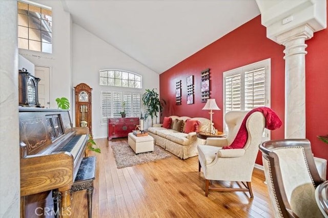 living room featuring hardwood / wood-style floors, high vaulted ceiling, and ornate columns