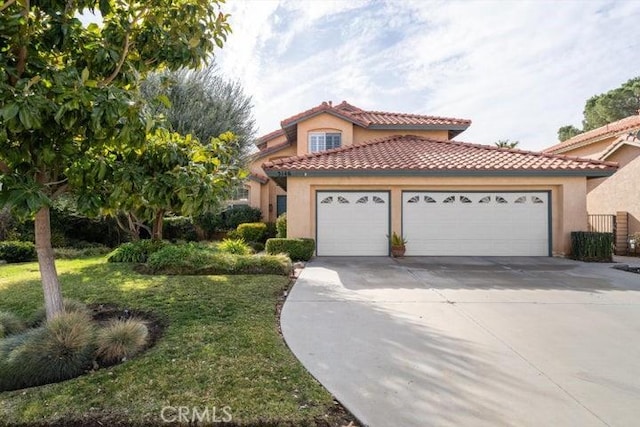 mediterranean / spanish home featuring a garage and a front yard