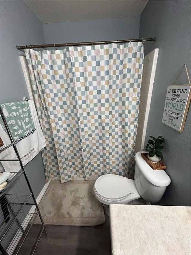 bathroom featuring hardwood / wood-style flooring, a shower with shower curtain, and toilet