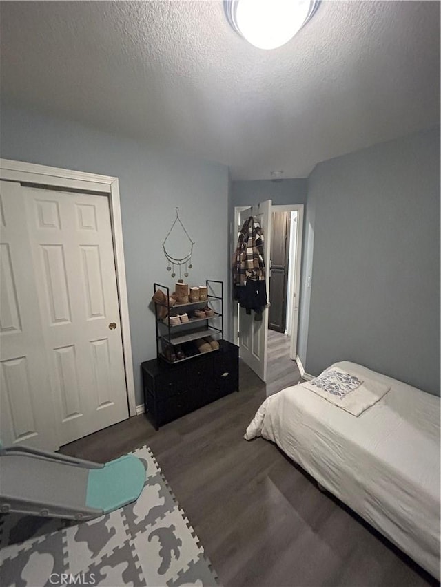 bedroom featuring dark wood-type flooring, a textured ceiling, and a closet