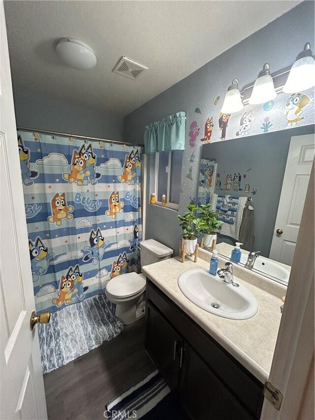 bathroom with hardwood / wood-style flooring, vanity, toilet, a textured ceiling, and a shower with shower curtain