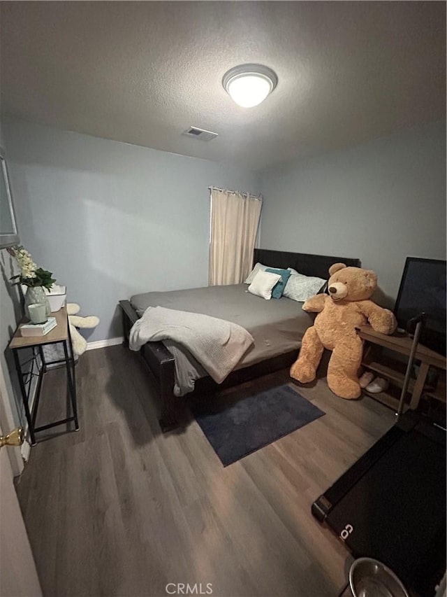 bedroom featuring hardwood / wood-style flooring and a textured ceiling