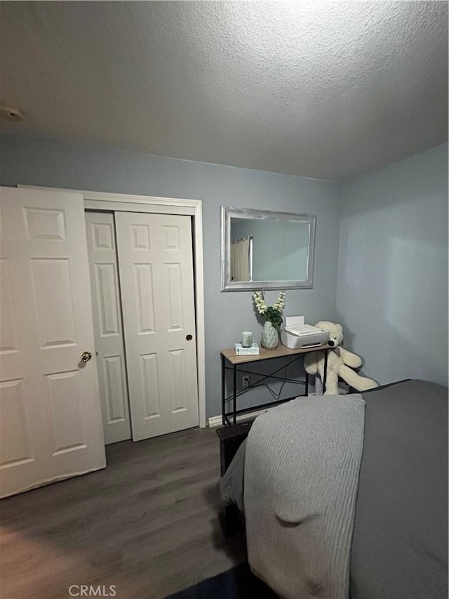 bedroom with dark wood-type flooring, a closet, and a textured ceiling