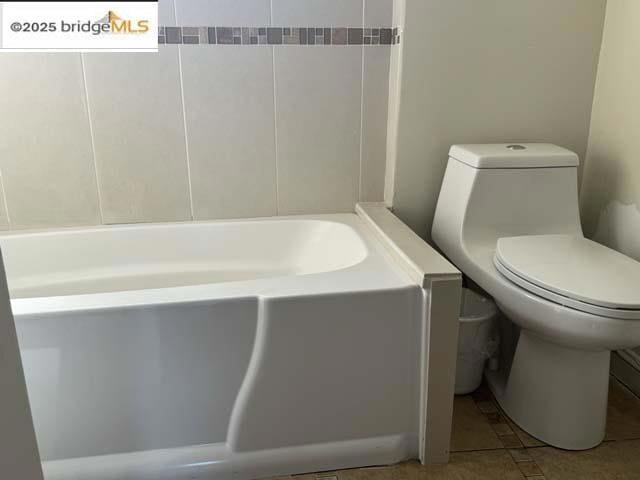 bathroom featuring a washtub, tile patterned flooring, and toilet