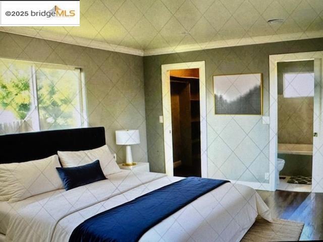 bedroom featuring wood-type flooring, tile walls, and ensuite bathroom