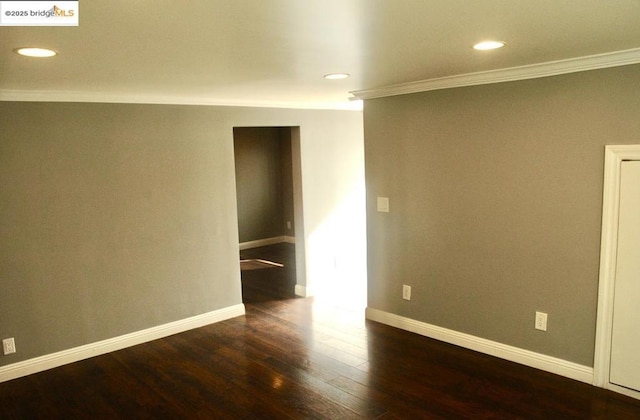 empty room with ornamental molding and dark wood-type flooring