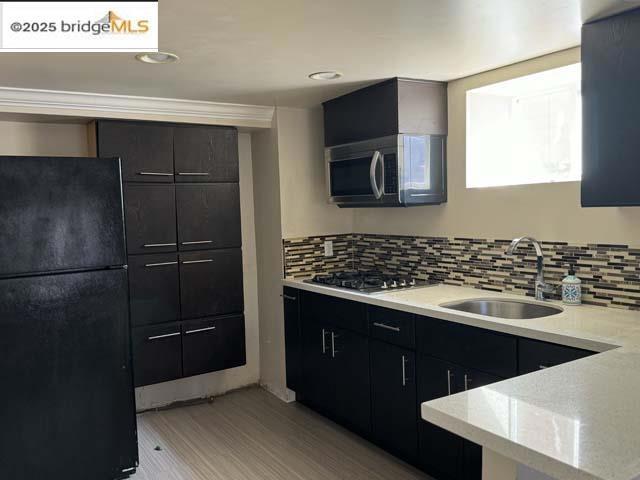 kitchen with appliances with stainless steel finishes, light hardwood / wood-style floors, sink, and decorative backsplash