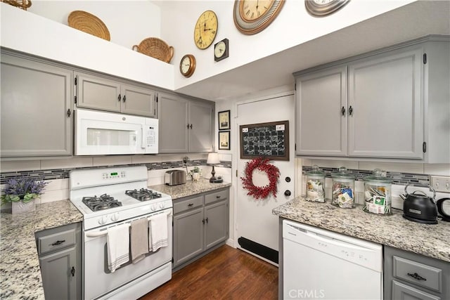 kitchen featuring light stone counters, white appliances, gray cabinetry, and decorative backsplash