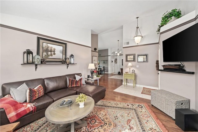 living area featuring a chandelier, visible vents, baseboards, and wood finished floors