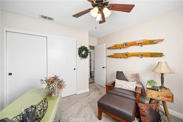 living area featuring light carpet, baseboards, visible vents, and a ceiling fan