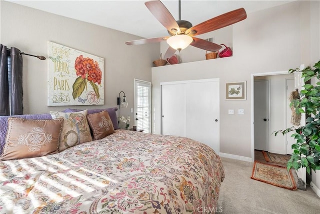 bedroom featuring light carpet, a towering ceiling, baseboards, a ceiling fan, and a closet