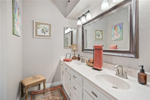 full bath with double vanity, baseboards, and a sink