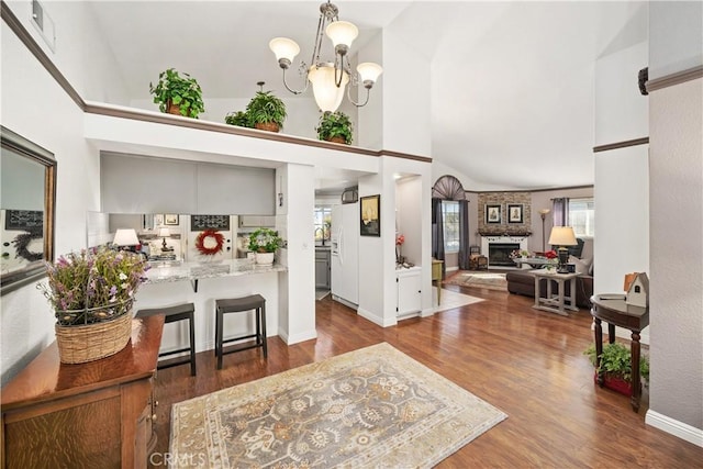 entrance foyer featuring a large fireplace, dark wood-type flooring, a towering ceiling, and an inviting chandelier