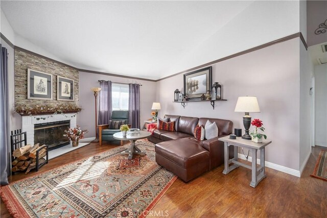 living room featuring hardwood / wood-style flooring, ornamental molding, and a brick fireplace