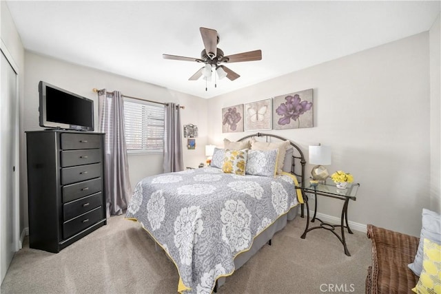 bedroom featuring light carpet, a ceiling fan, baseboards, and a closet