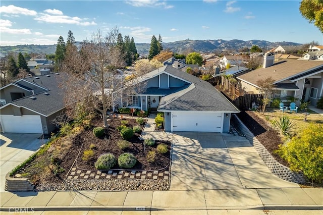 view of front facade with roof with shingles, a mountain view, a garage, a residential view, and driveway