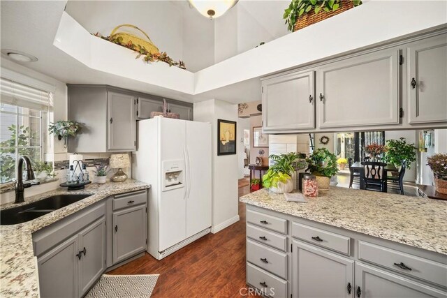 kitchen with white refrigerator with ice dispenser, sink, gray cabinetry, and dark hardwood / wood-style flooring