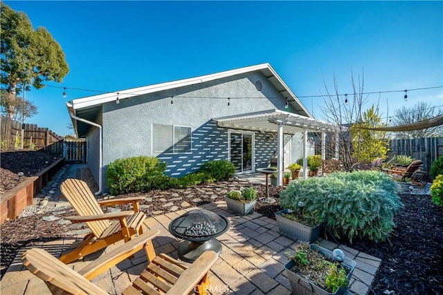 back of property featuring a fire pit, fence, stucco siding, a pergola, and a patio area