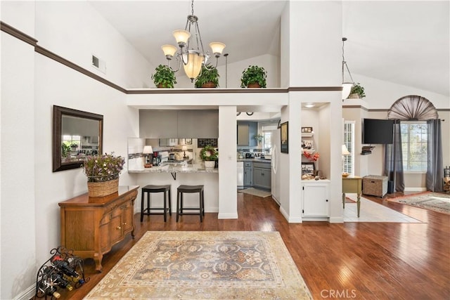 interior space with a breakfast bar, high vaulted ceiling, visible vents, dark wood-type flooring, and a chandelier