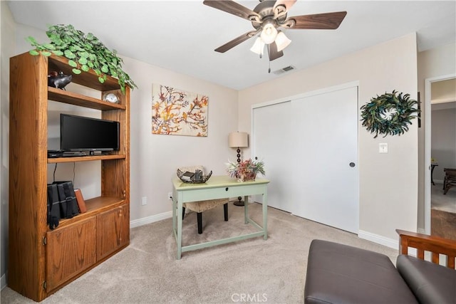 home office with baseboards, a ceiling fan, visible vents, and light colored carpet