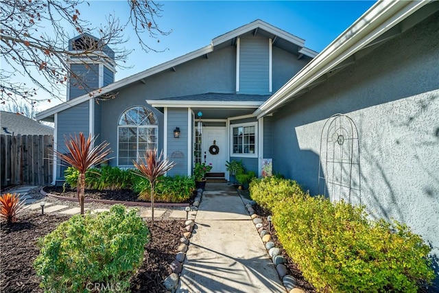 doorway to property with fence and stucco siding