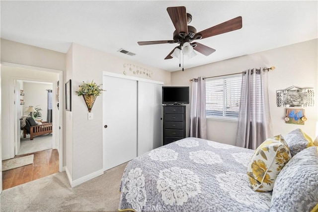 bedroom featuring light colored carpet, a ceiling fan, baseboards, visible vents, and a closet