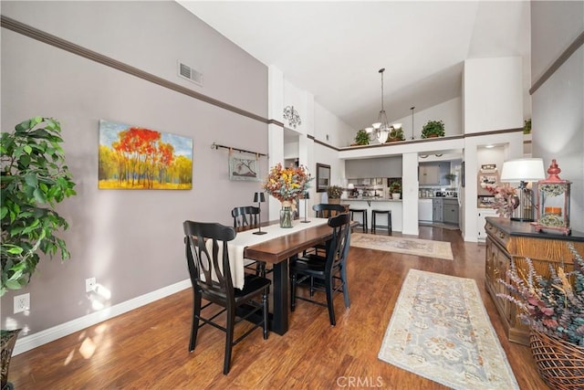 dining space featuring a notable chandelier, visible vents, wood finished floors, high vaulted ceiling, and baseboards