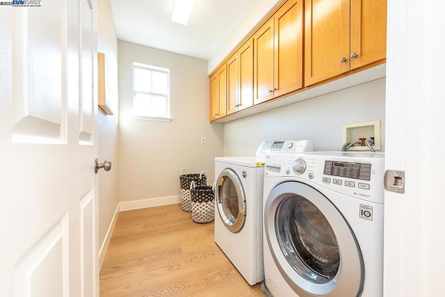 laundry area with separate washer and dryer, light hardwood / wood-style floors, and cabinets