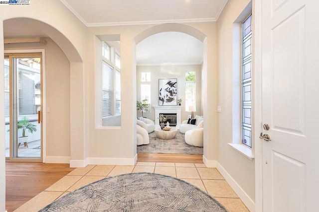 tiled foyer featuring crown molding and a healthy amount of sunlight