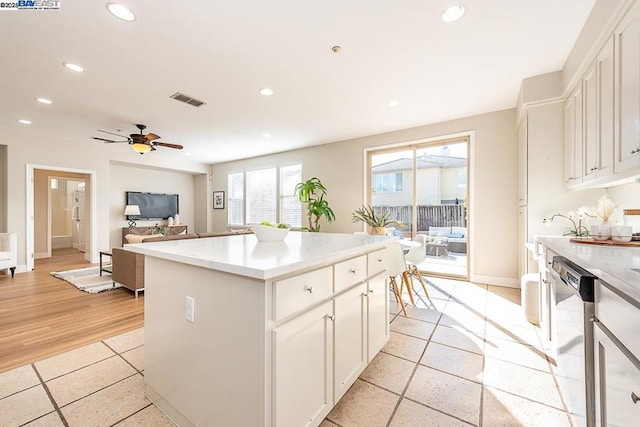 kitchen featuring light tile patterned floors, ceiling fan, white cabinetry, a center island, and stainless steel dishwasher