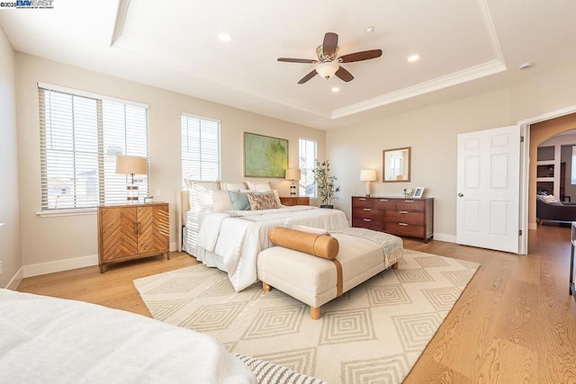 bedroom featuring ceiling fan, a tray ceiling, and light hardwood / wood-style floors