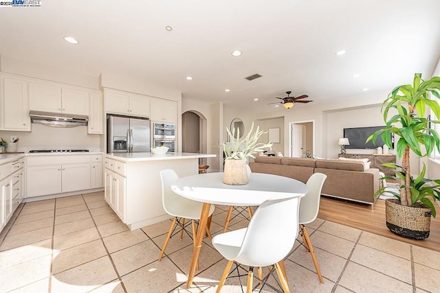 kitchen featuring stainless steel refrigerator with ice dispenser, black stovetop, white cabinets, a kitchen island, and light tile patterned flooring