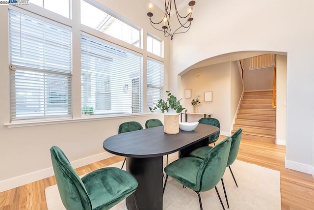 dining room with light hardwood / wood-style flooring, a chandelier, and a high ceiling