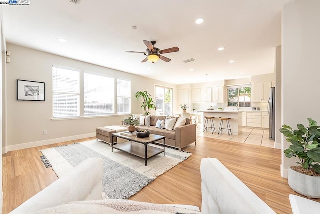 living room featuring ceiling fan, a wealth of natural light, and light hardwood / wood-style floors