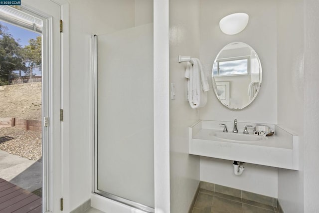 bathroom featuring a shower with door and sink