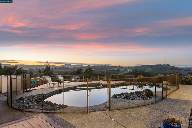 pool at dusk featuring a water and mountain view