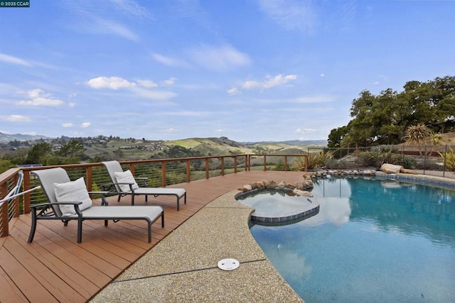 view of swimming pool with a deck with mountain view and an in ground hot tub