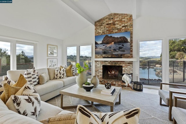 living room with a water view, a fireplace, and high vaulted ceiling