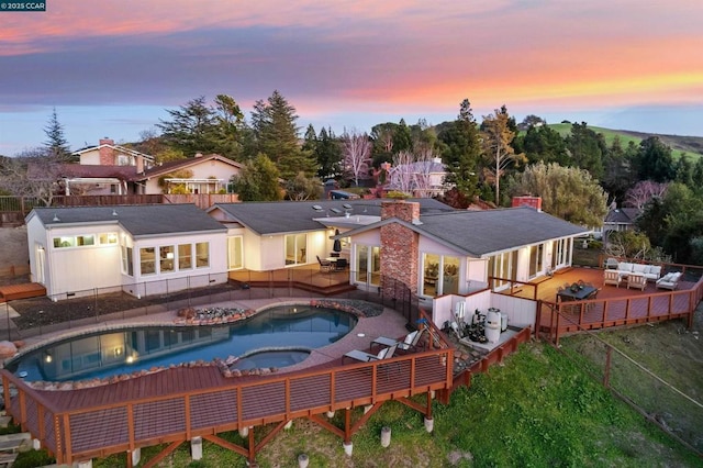 back house at dusk featuring an outdoor hangout area and an in ground hot tub